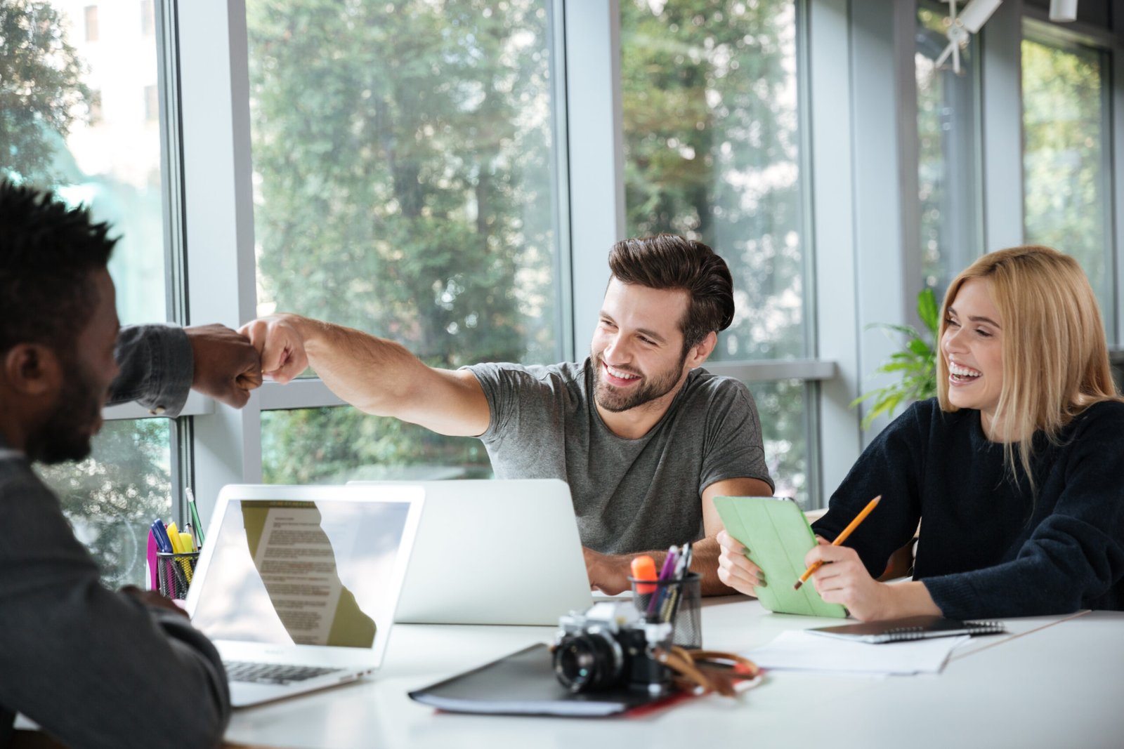 smiling-young-colleagues-sitting-office-coworking-scaled.jpg